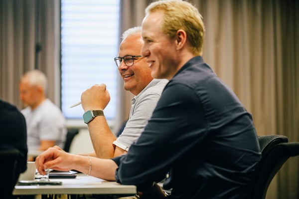 Anders Sørensen og Henrik Svendsgård ler ved et møtebord